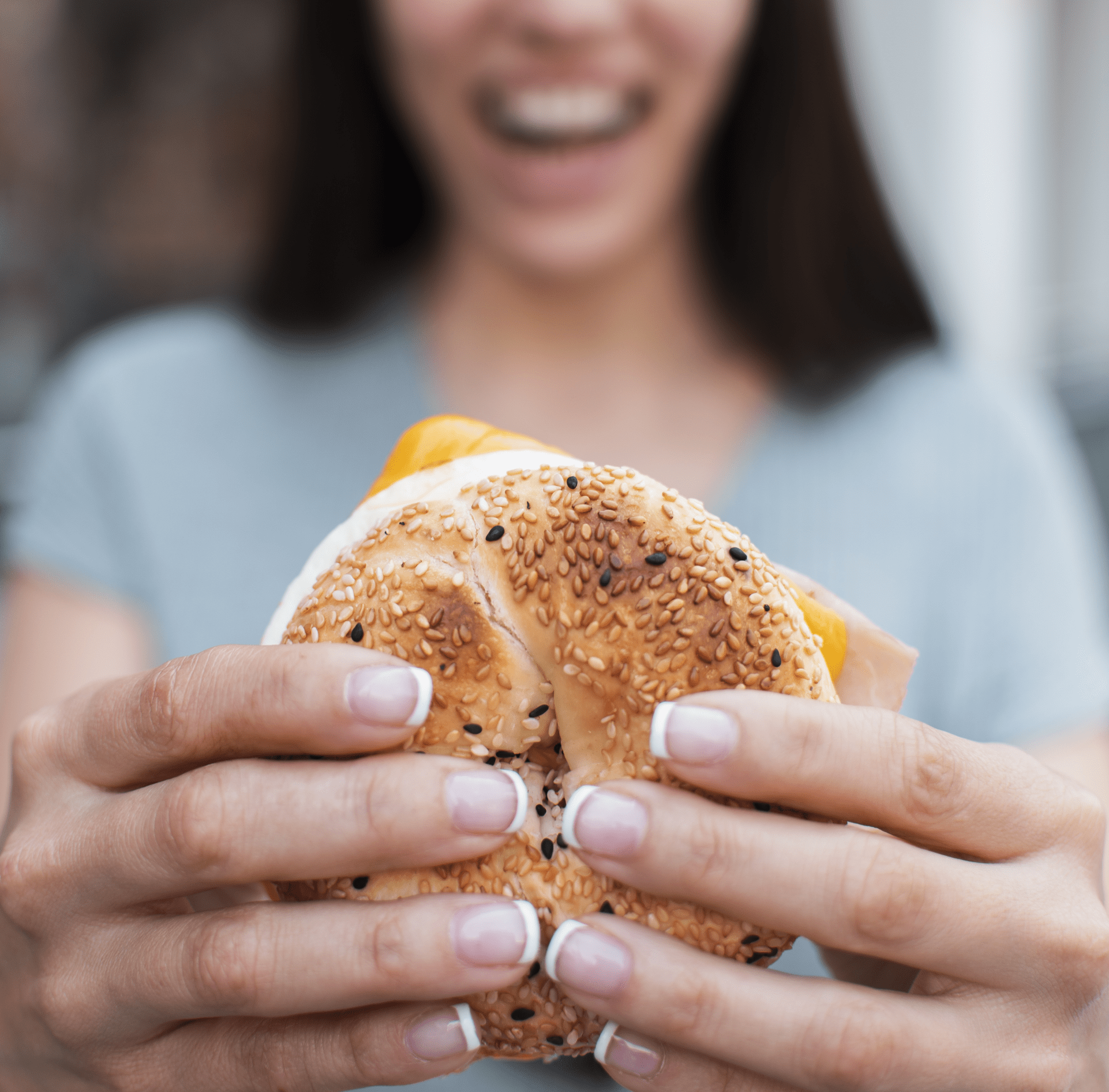 image of a women holding a bagel sandwich.